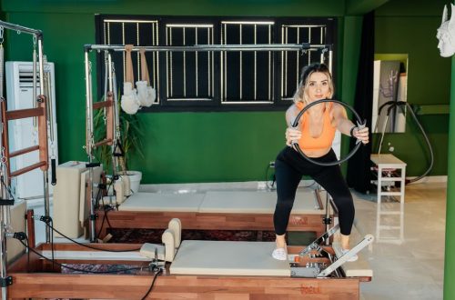 Fitness enthusiast practicing Pilates on a reformer machine in a modern, brightly lit studio.